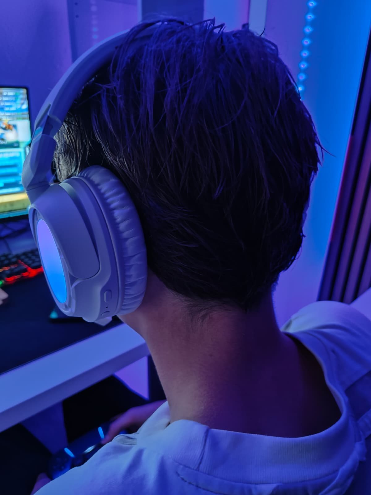 De HyperX Cloud Flight 2 op het hoofd aan een gamingopstelling, met blauwe verlichting in de oorschelp
