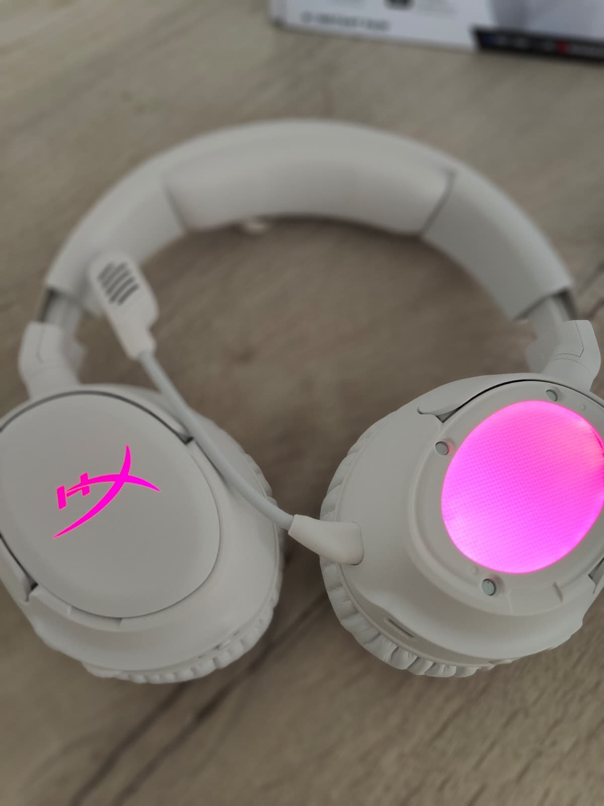 HyperX Cloud Flight 2 in het wit met één plaat van de oorschelp gehaald, zodat de roze verlichting zichtbaar is