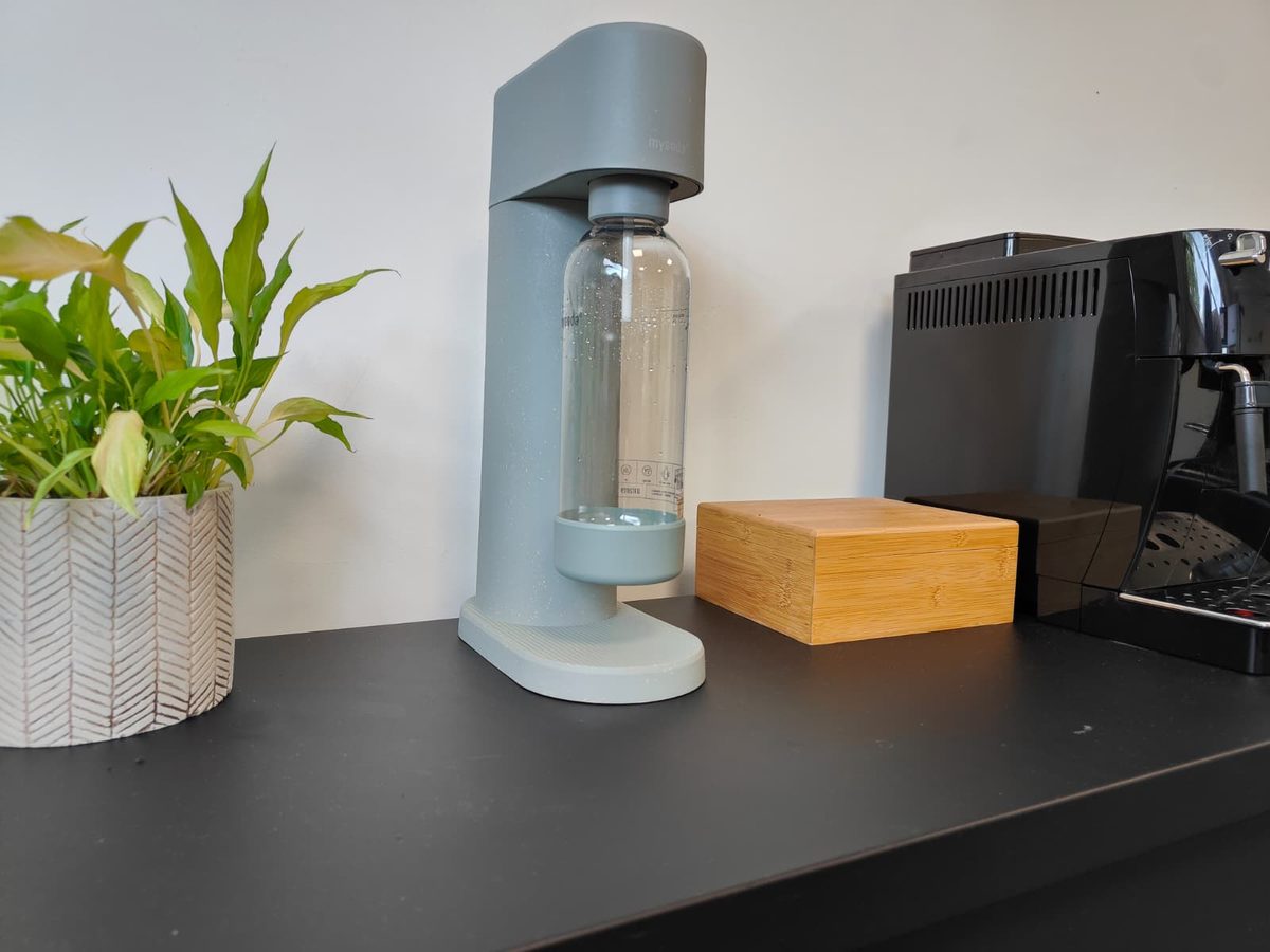 Mysoda Woody op een zwart bureau naast een koffiemachine op kantoor