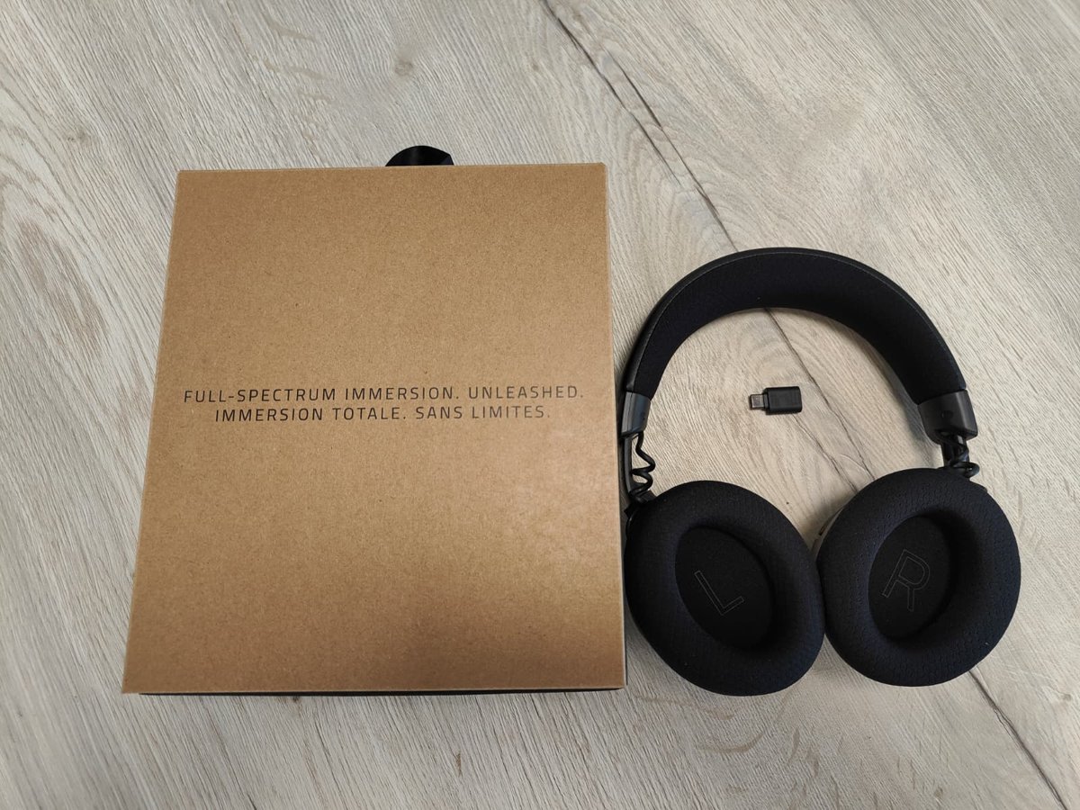 Bruin kartonnen boekje, de USB-C-dongle en de Razer Kraken V4 naast elkaar